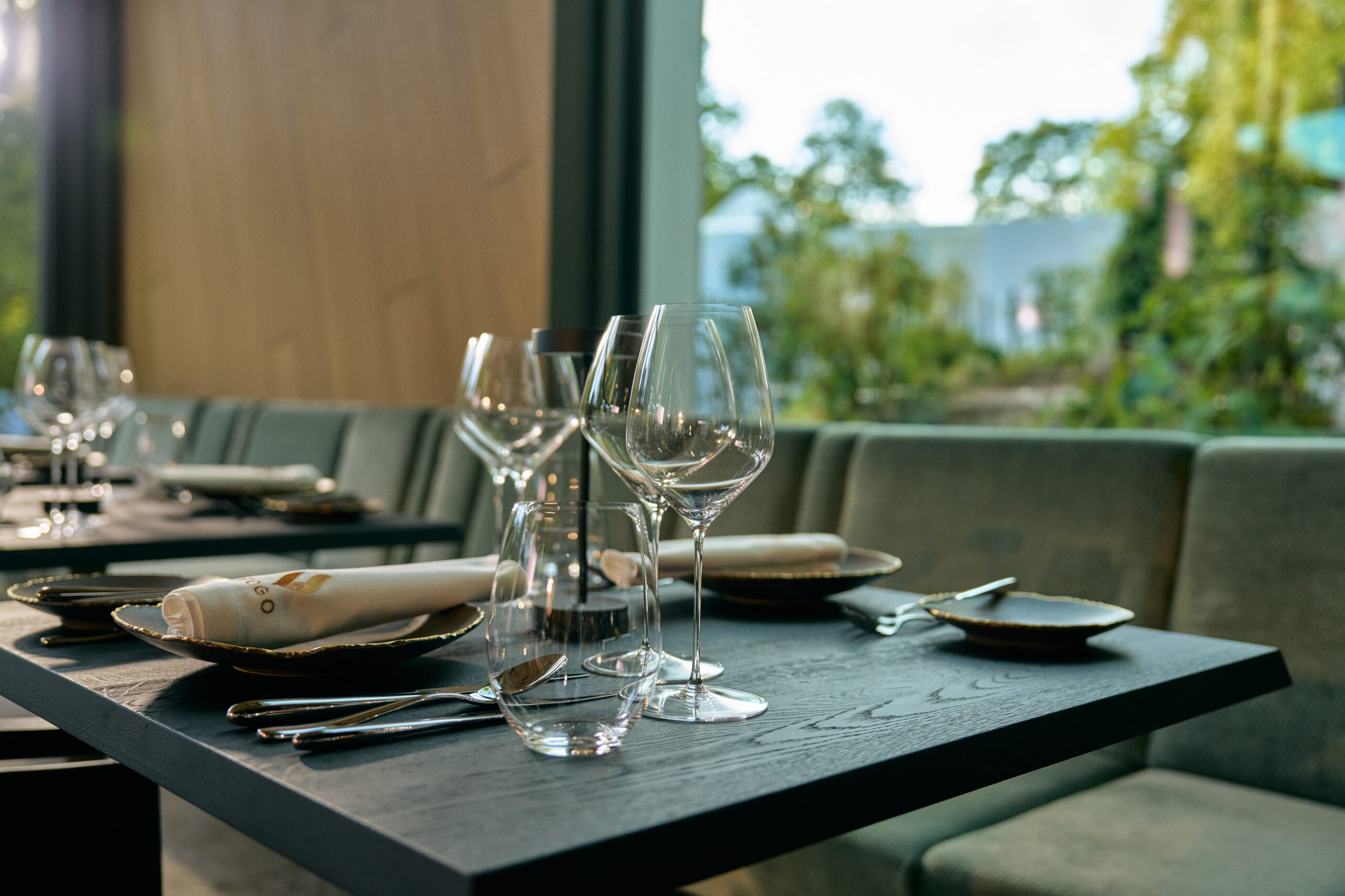 Elegant gedeckter Tisch mit Weingläsern, Stoffservietten und Blick ins Grüne im Fine Dining Restaurant des Alea Resorts